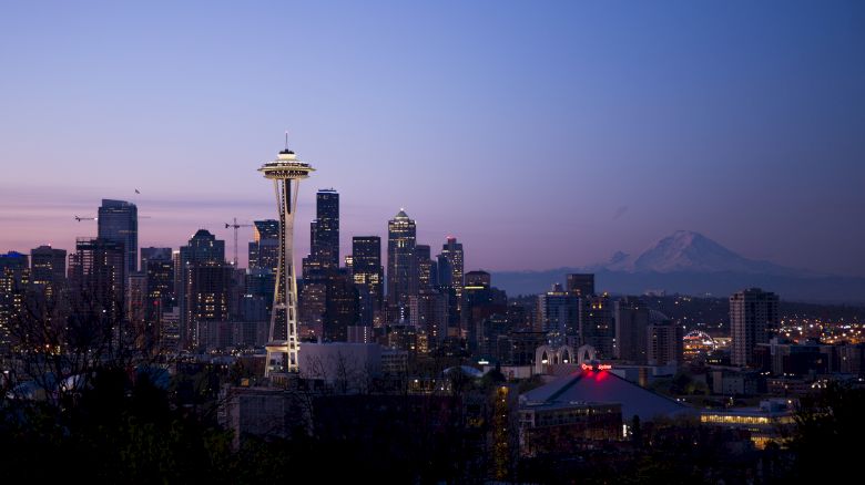A twilight view of the Seattle skyline featuring the Space Needle, downtown buildings, and Mount Rainier in the background, creating a serene ambiance.