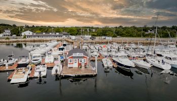 The image shows a marina with various boats docked and a building labeled 