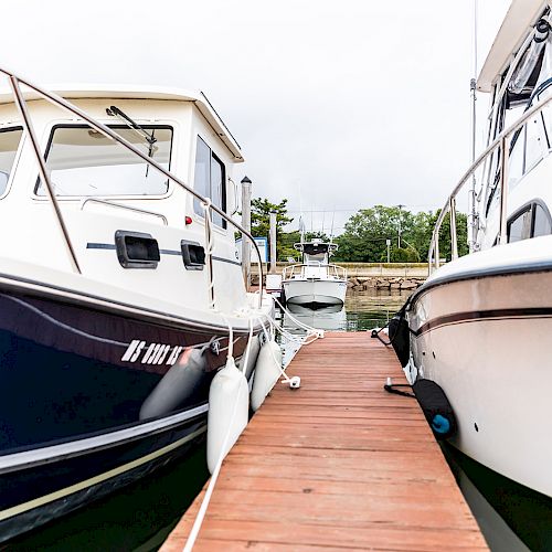 Two boats are docked at a wooden pier, facing each other from either side of the walkway.